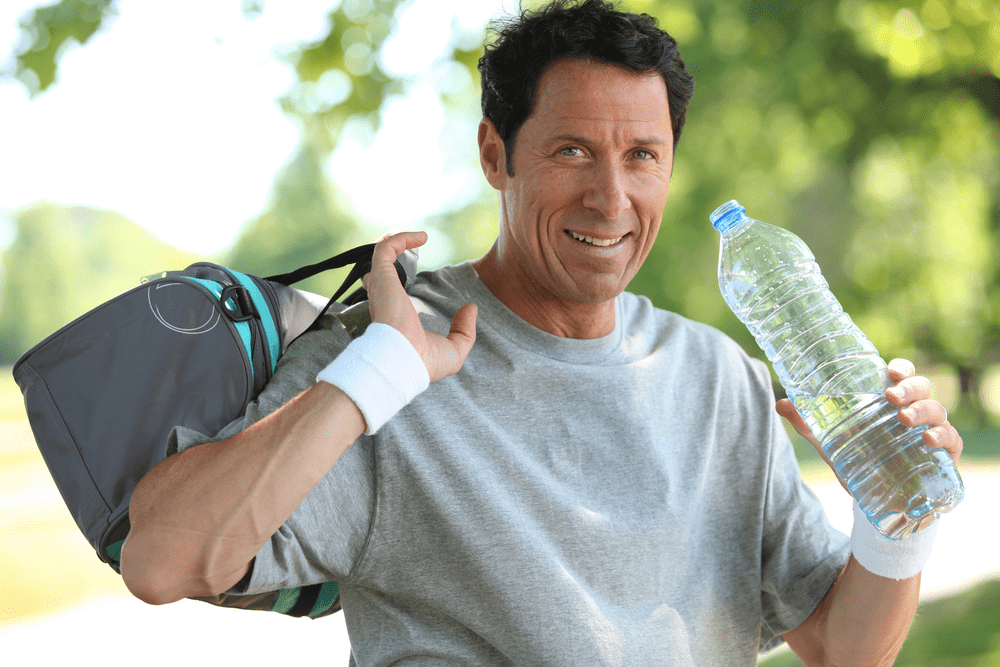 Active older man outside with gym bag and water