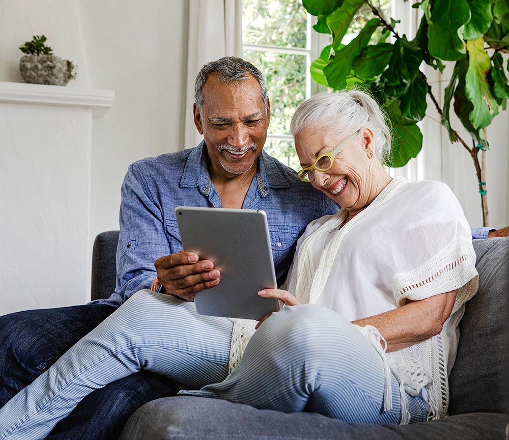Happy couple inside looking at a tablet